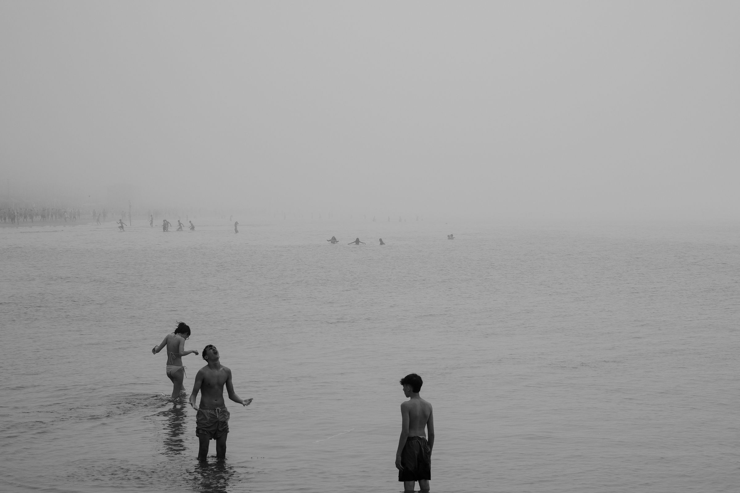 Three figures wading into a foggy sea