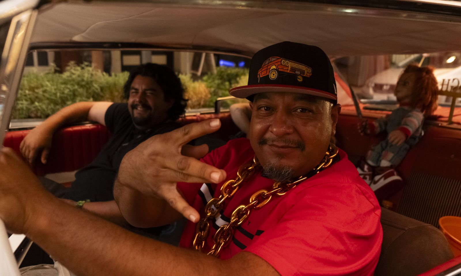 Two men smiling from the front seat of a classic car
