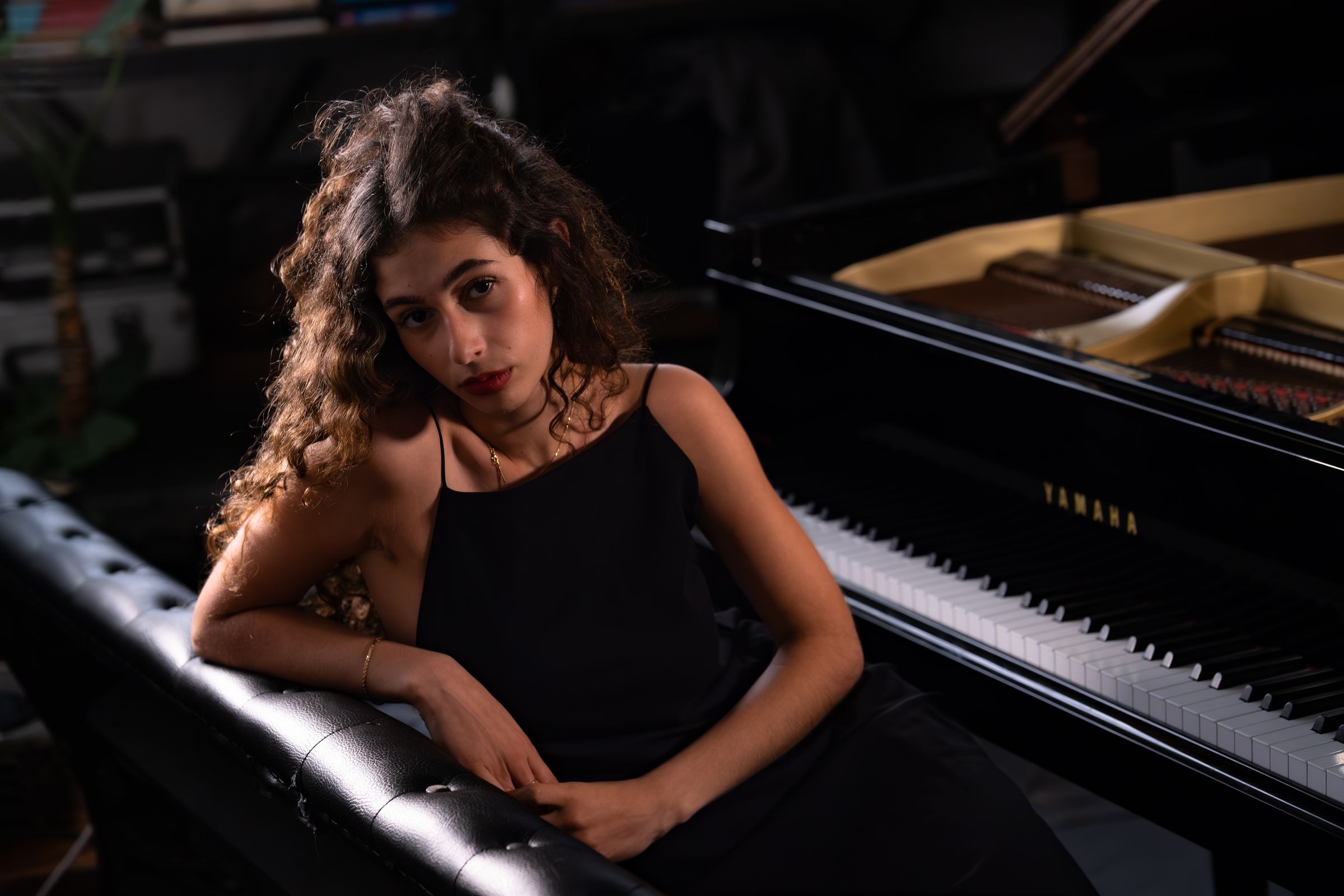 Young woman with curly hair leaning on a grand piano