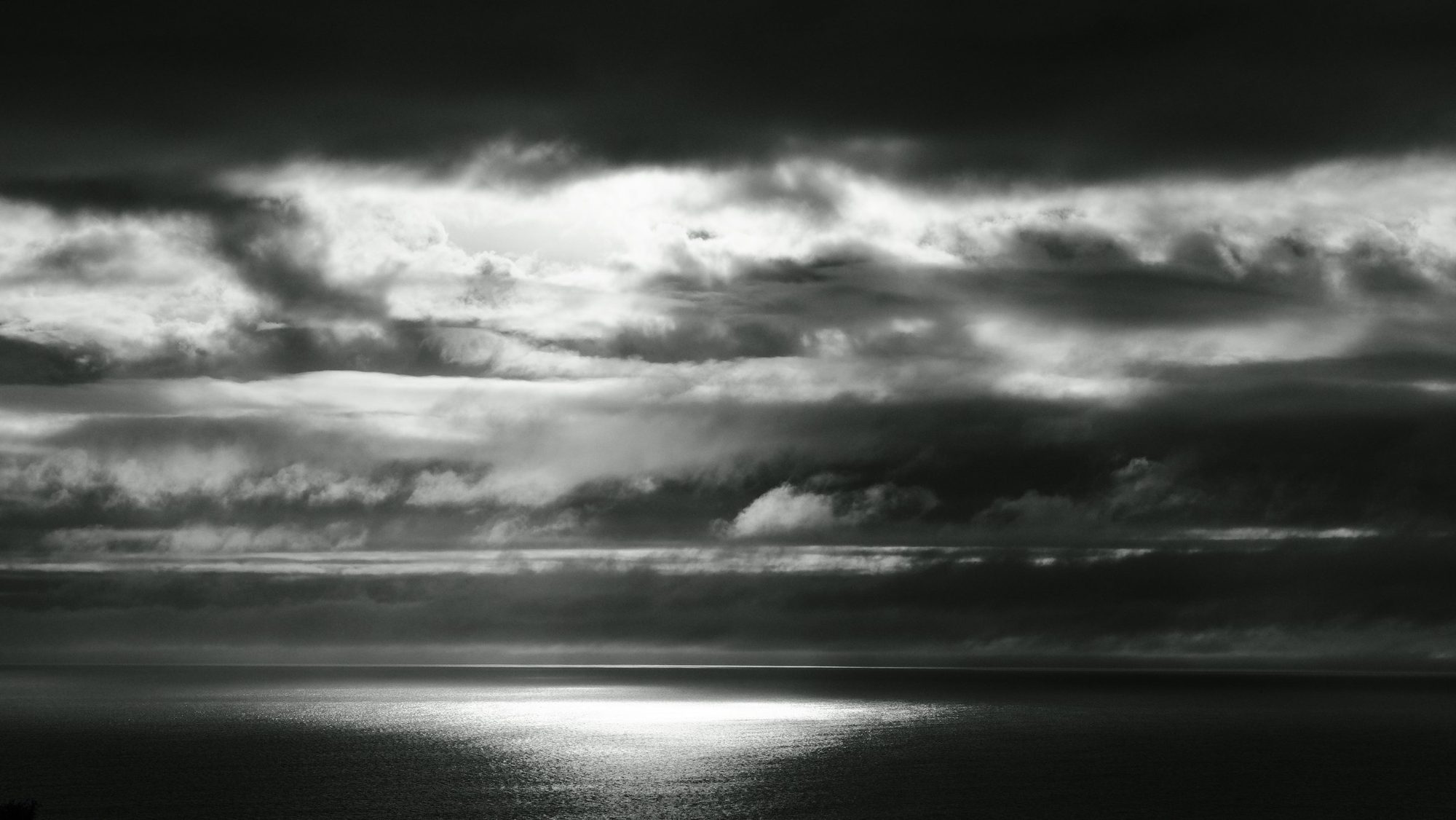 Light breaking through storm clouds onto a dark sea